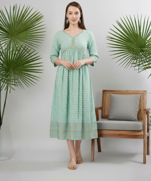 Woman wearing sea green floral print A-line dress with V-neck, gold lace trim and golden border hem